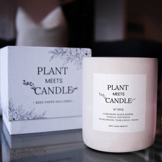 Light grey concrete candle vessel for Plant Meets Candle No. Five is highlighted alongside its product box in a dark interior.