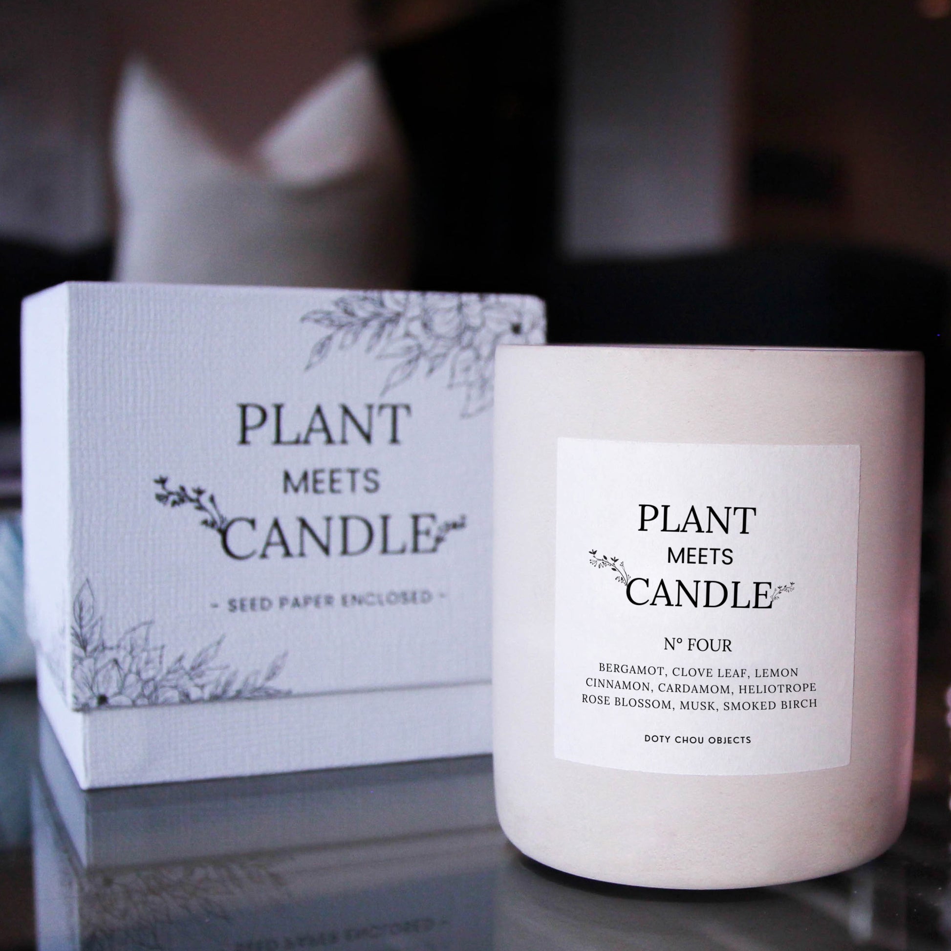 Light grey concrete candle vessel for Plant Meets Candle No. Four is highlighted alongside its product box in a dark interior.