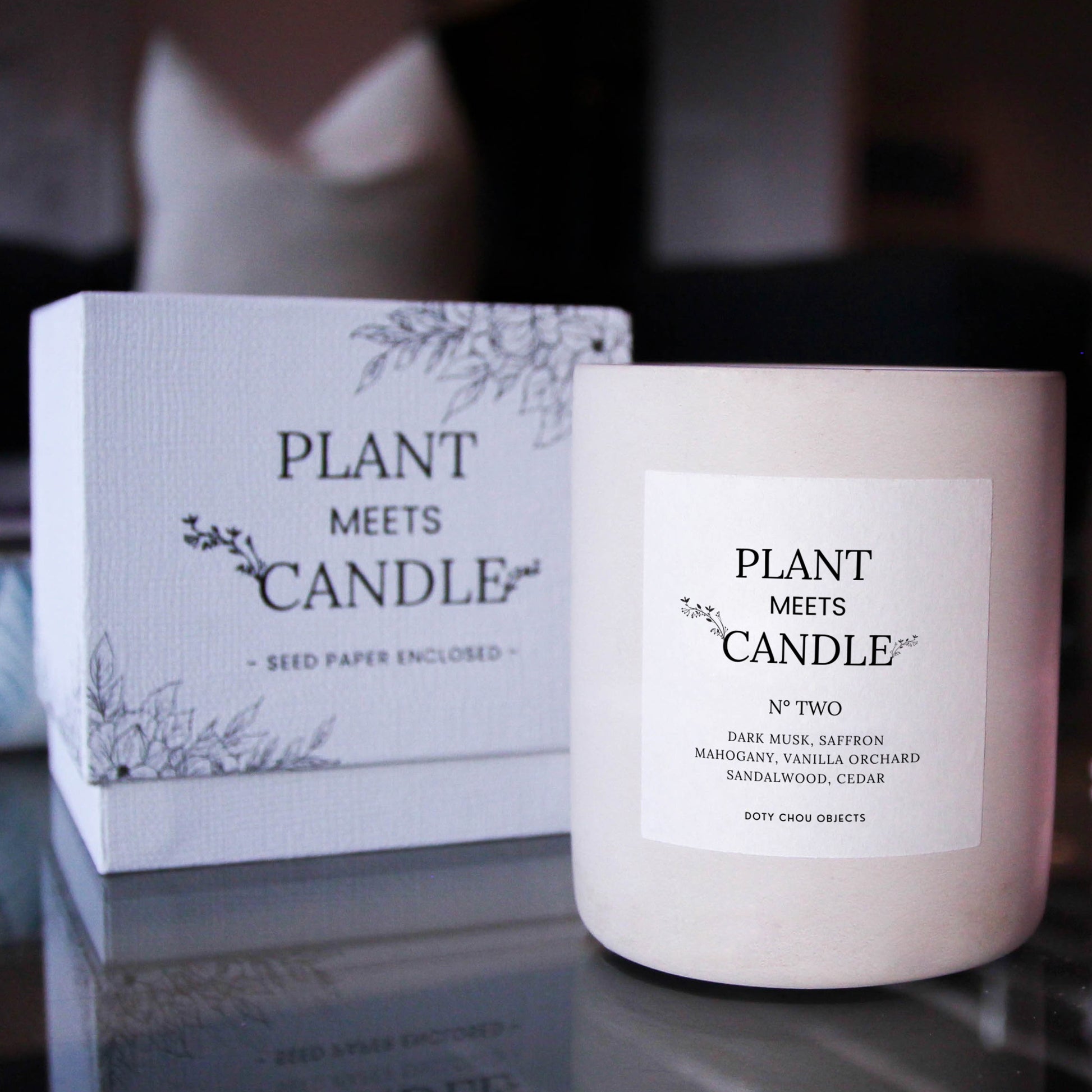 Light grey concrete candle vessel for Plant Meets Candle No. Two is highlighted alongside its product box in a dark interior.