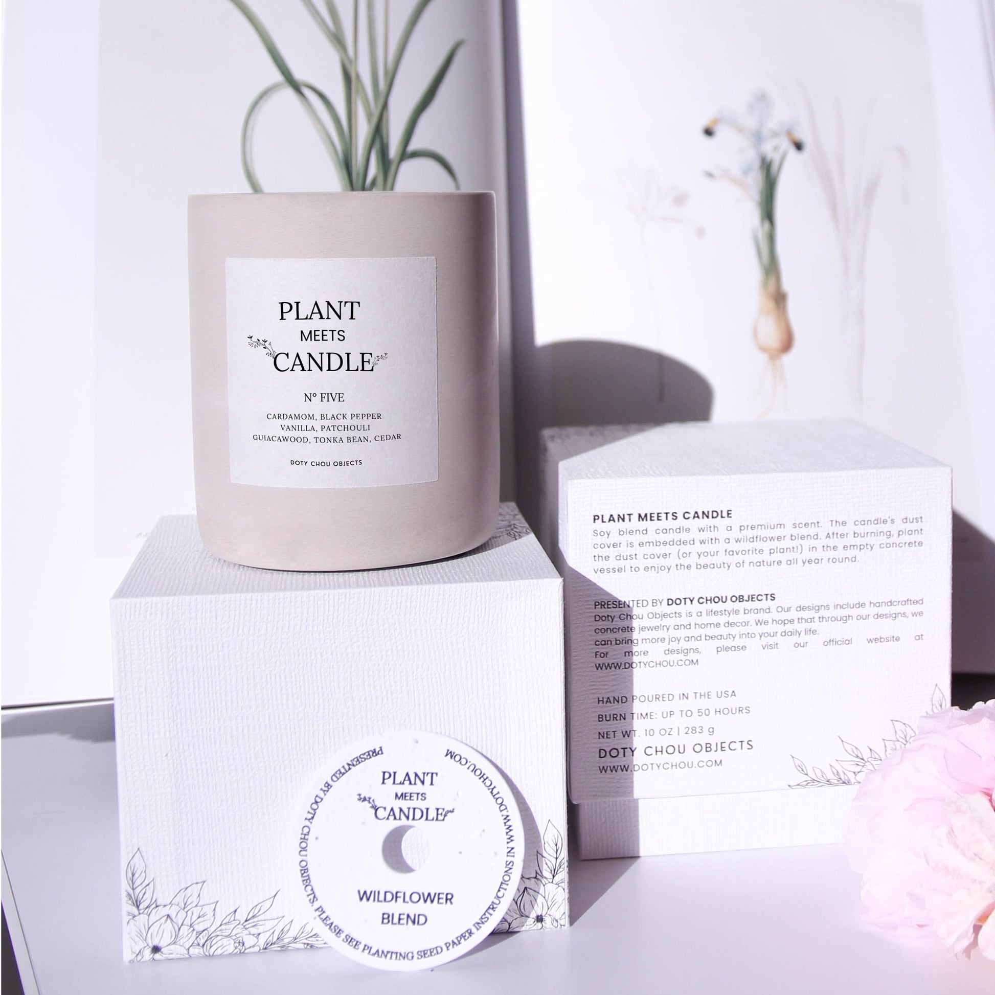 A light grey concrete vessel containing Plant Meets Candle No. Five displayed with botanical images alongside its product box and seed paper dustcover.